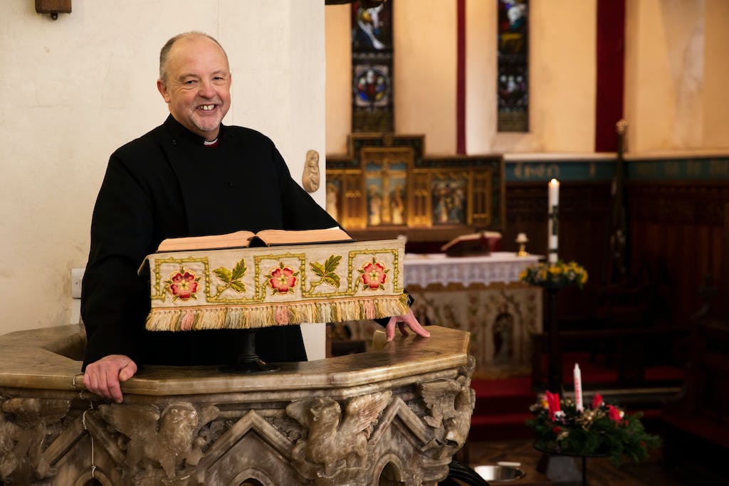 A priest is standing in front of a church altar