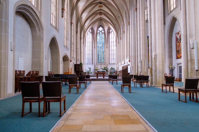 Gothic-style church interior with rows of chairs and an ornate altar.